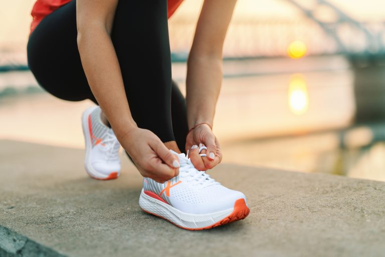 Picture of a woman kneeling down and tying her steadfast white shoes